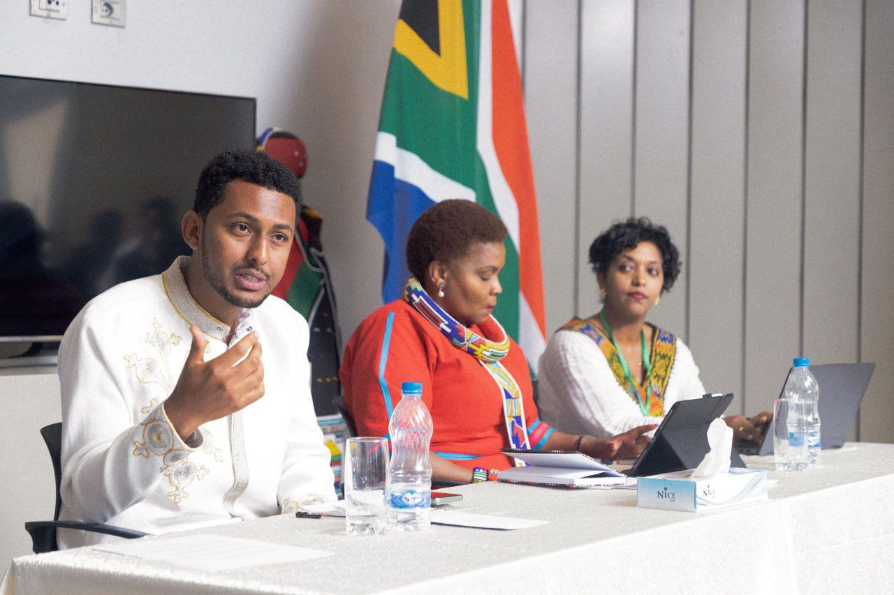 Speakers at the panel table with the South African flag